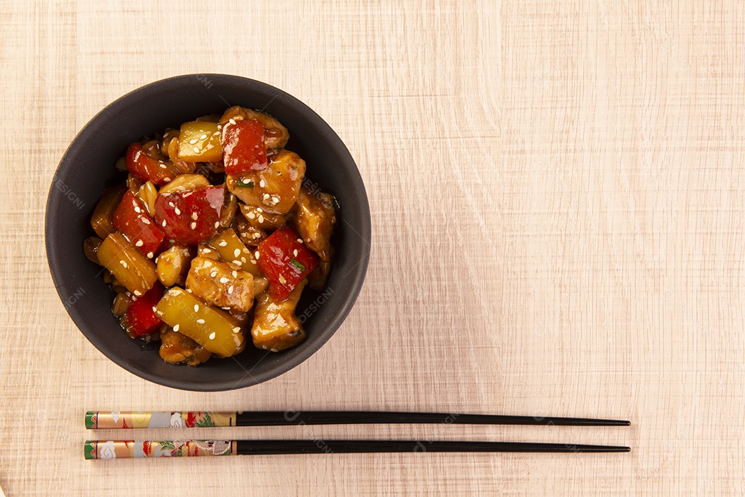 Frango xadrez em tigela amarela sobre fundo de madeira - comida chinesa