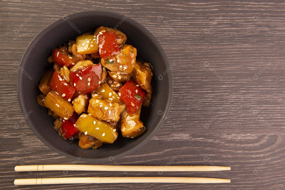 Frango xadrez em tigela amarela sobre fundo de madeira - comida chinesa
