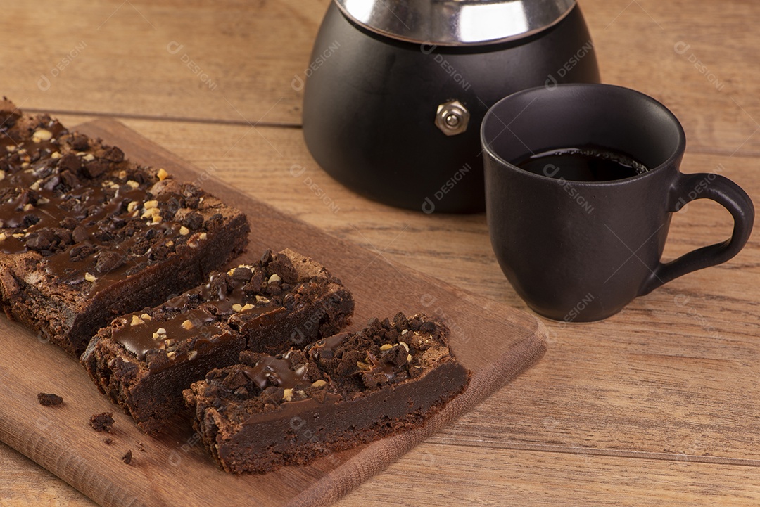 Algumas fatias de brownie na madeira, uma cafeteira e uma xícara de café