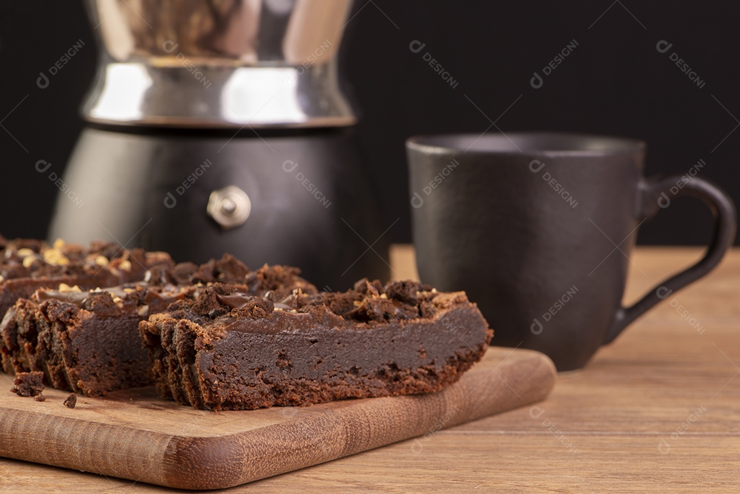 Algumas fatias de brownie na madeira, uma cafeteira e uma xícara de café