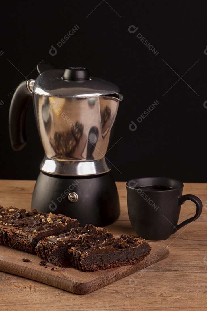 Algumas fatias de brownie na madeira, uma cafeteira e uma xícara de café