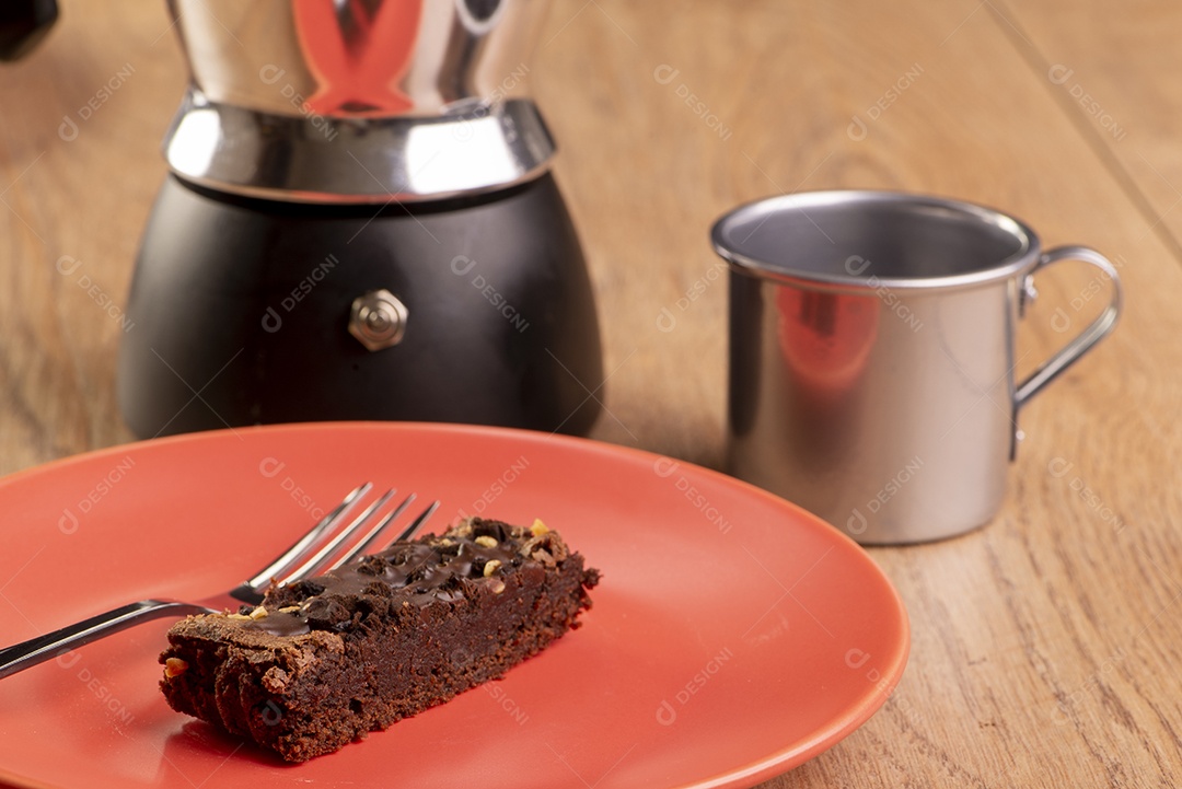 Prato com uma fatia de brownie, uma cafeteira e uma xícara de café