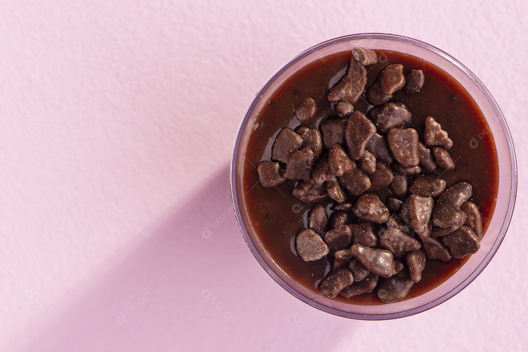 Copos de acrílico com brigadeiro e granulado de chocolate em fundo lilás.