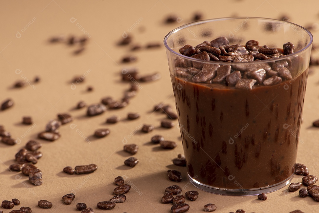 Copo de acrílico com brigadeiro e granulado de chocolate no fundo rosa