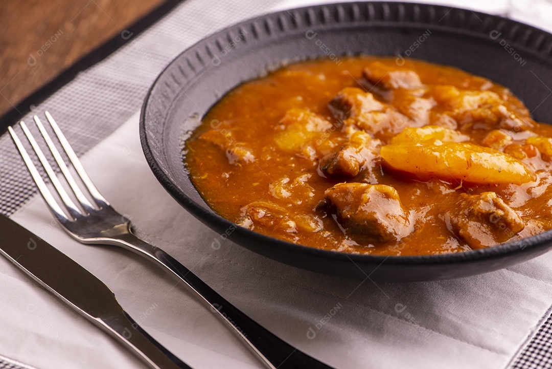 Prato com mandioca cozida e carne na mesa de madeira