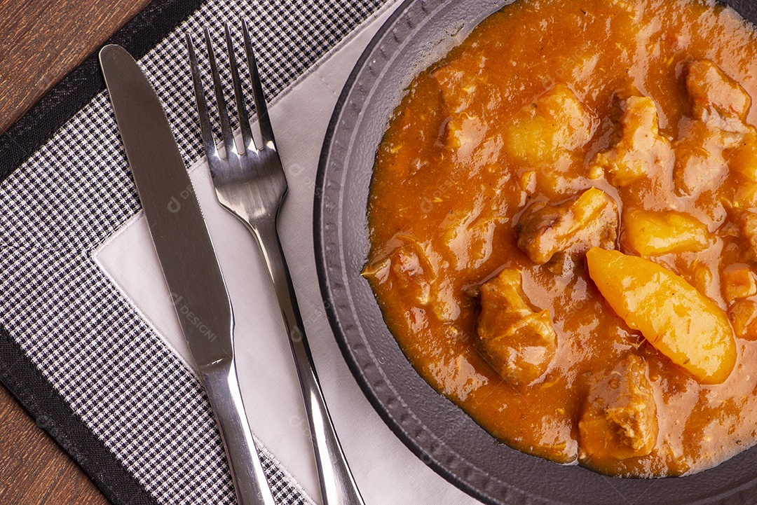 Prato com mandioca cozida e carne na mesa de madeira