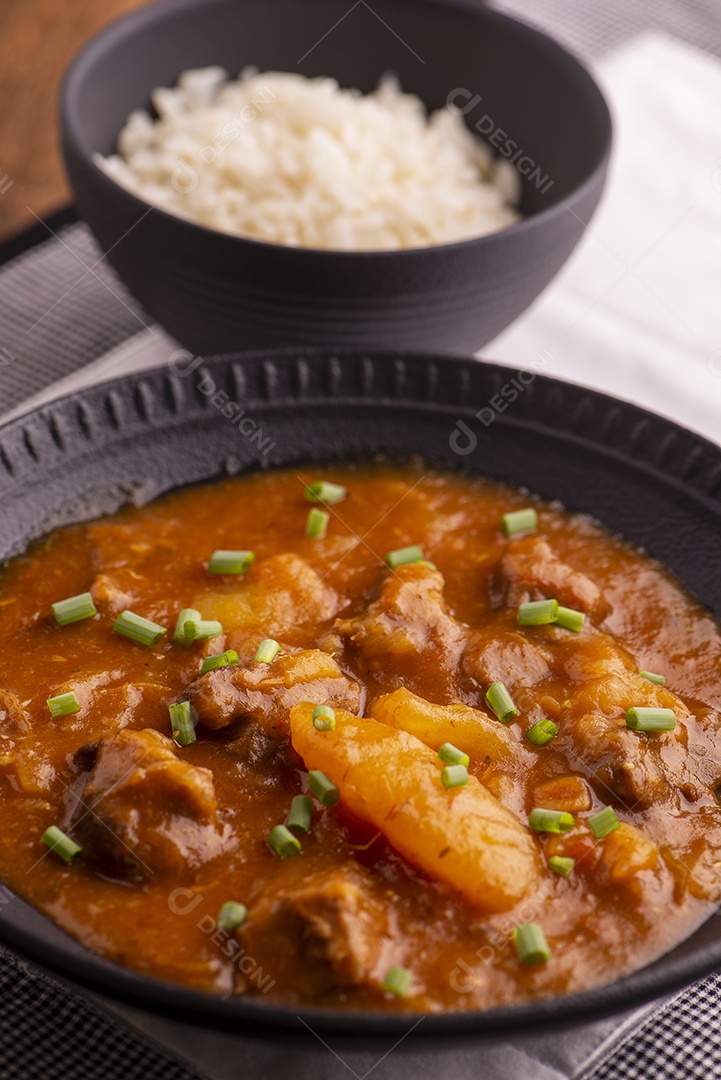 Prato com mandioca cozida e carne na mesa de madeira