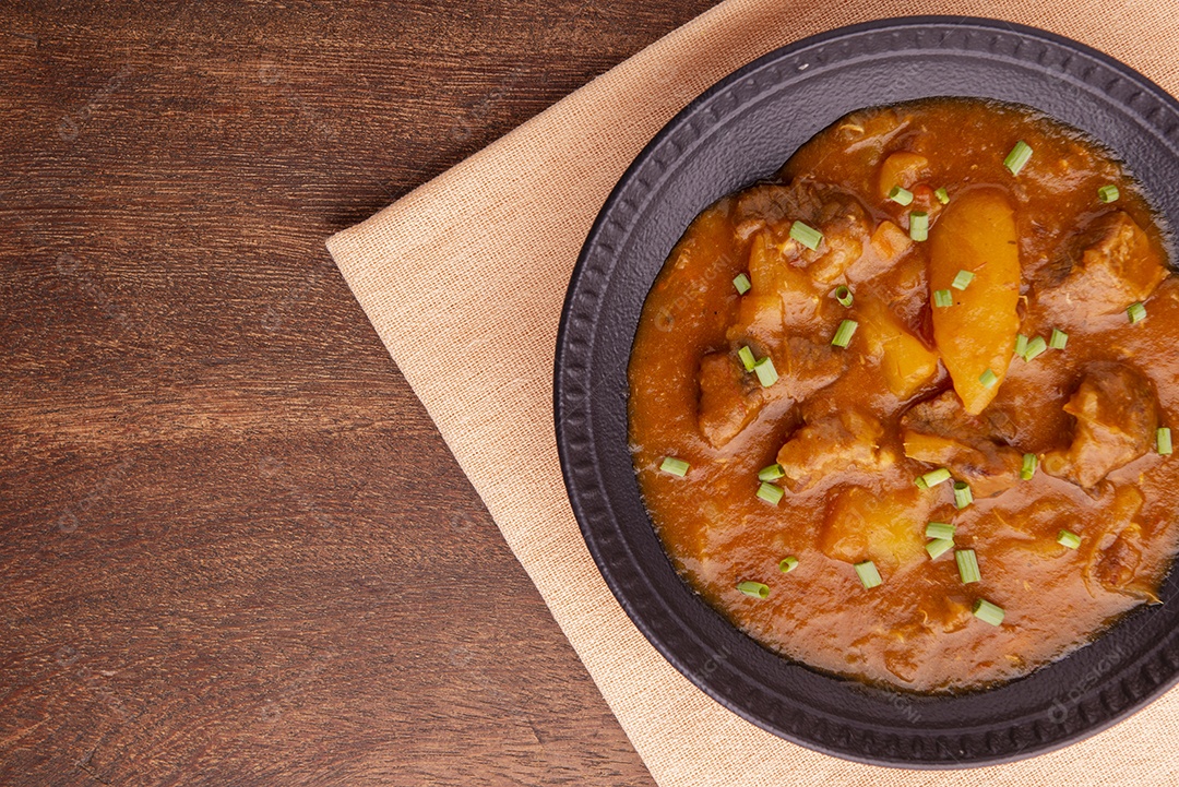 Prato com mandioca cozida e carne na mesa de madeira