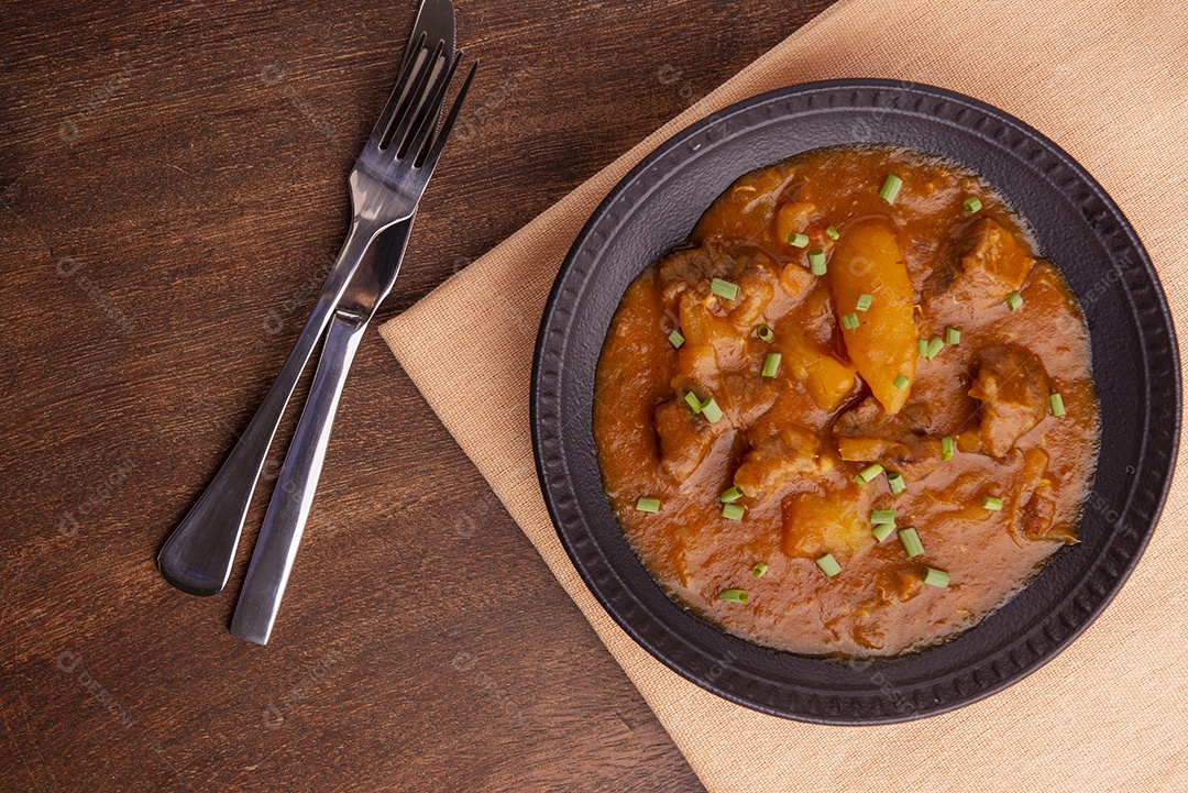 Prato com mandioca cozida e carne na mesa de madeira