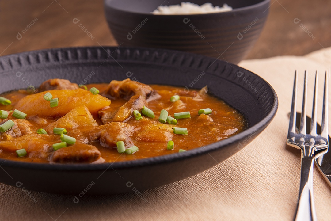 Prato com mandioca cozida e carne na mesa de madeira