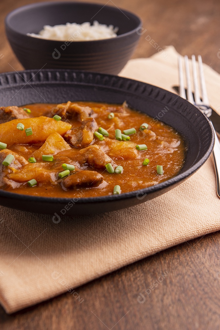 Prato com mandioca cozida e carne na mesa de madeira