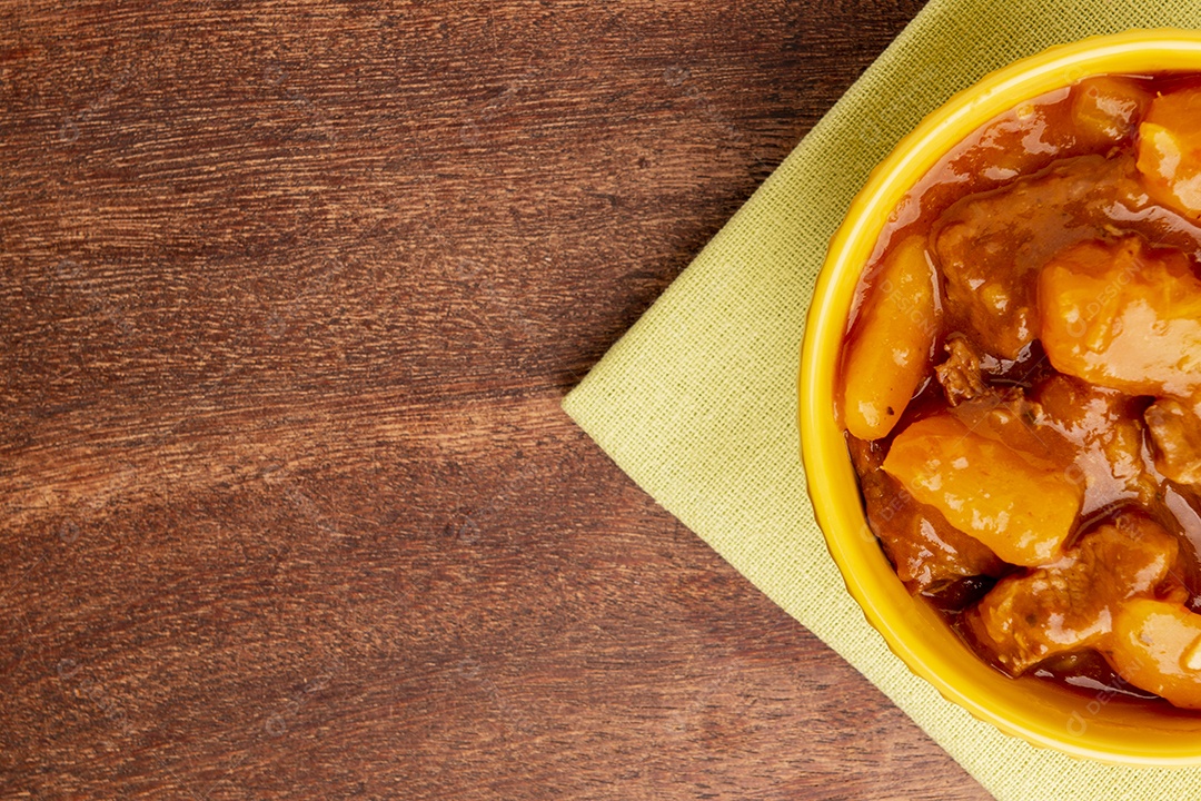 Prato com mandioca cozida e carne na mesa de madeira