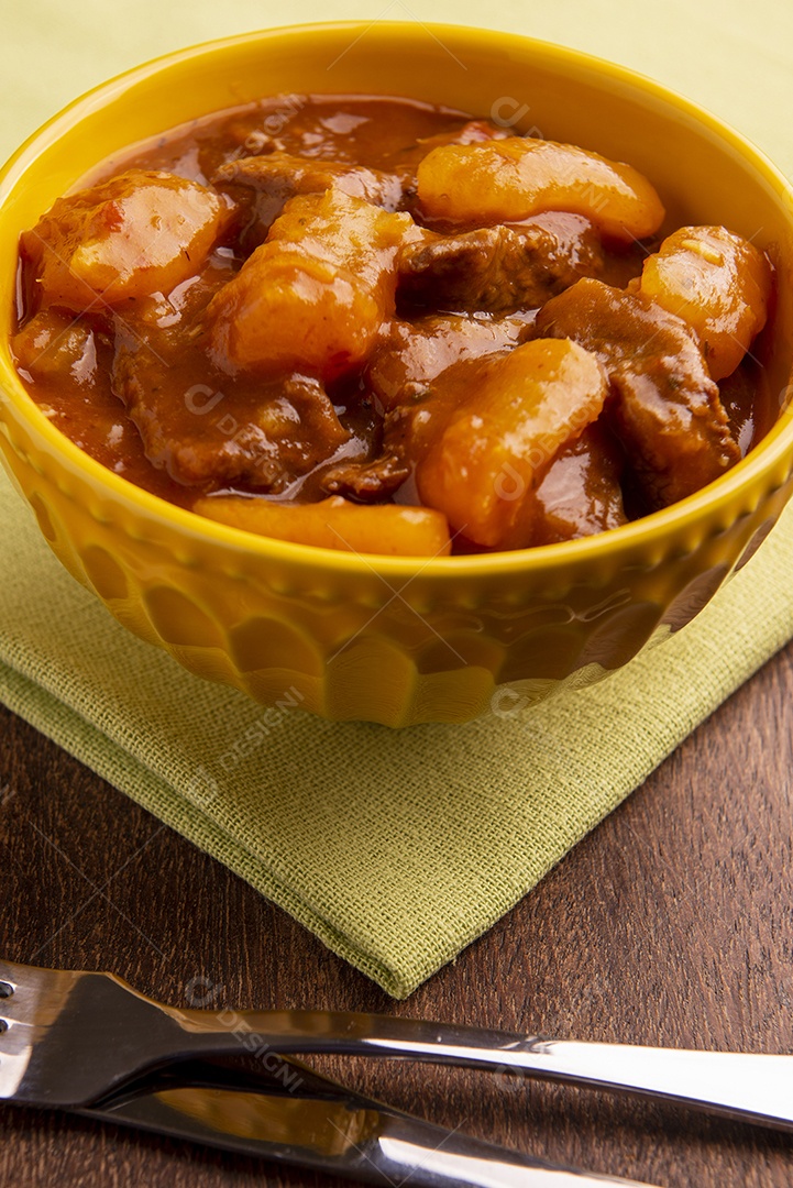 Prato com mandioca cozida e carne na mesa de madeira