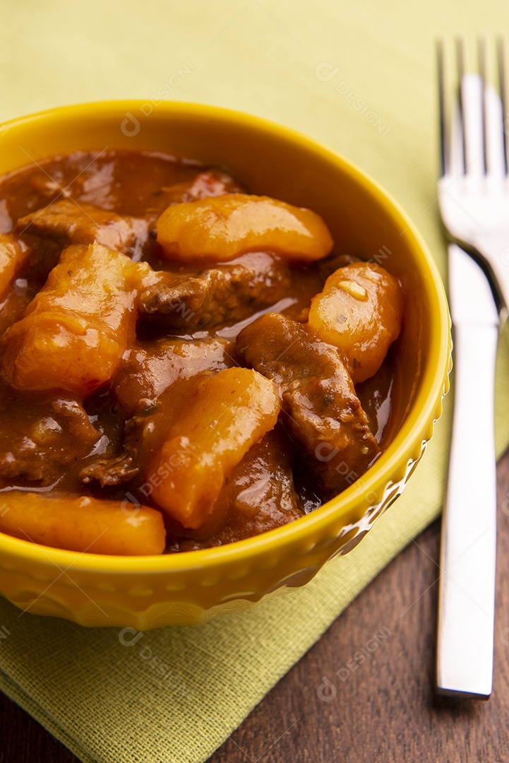 Prato com mandioca cozida e carne na mesa de madeira