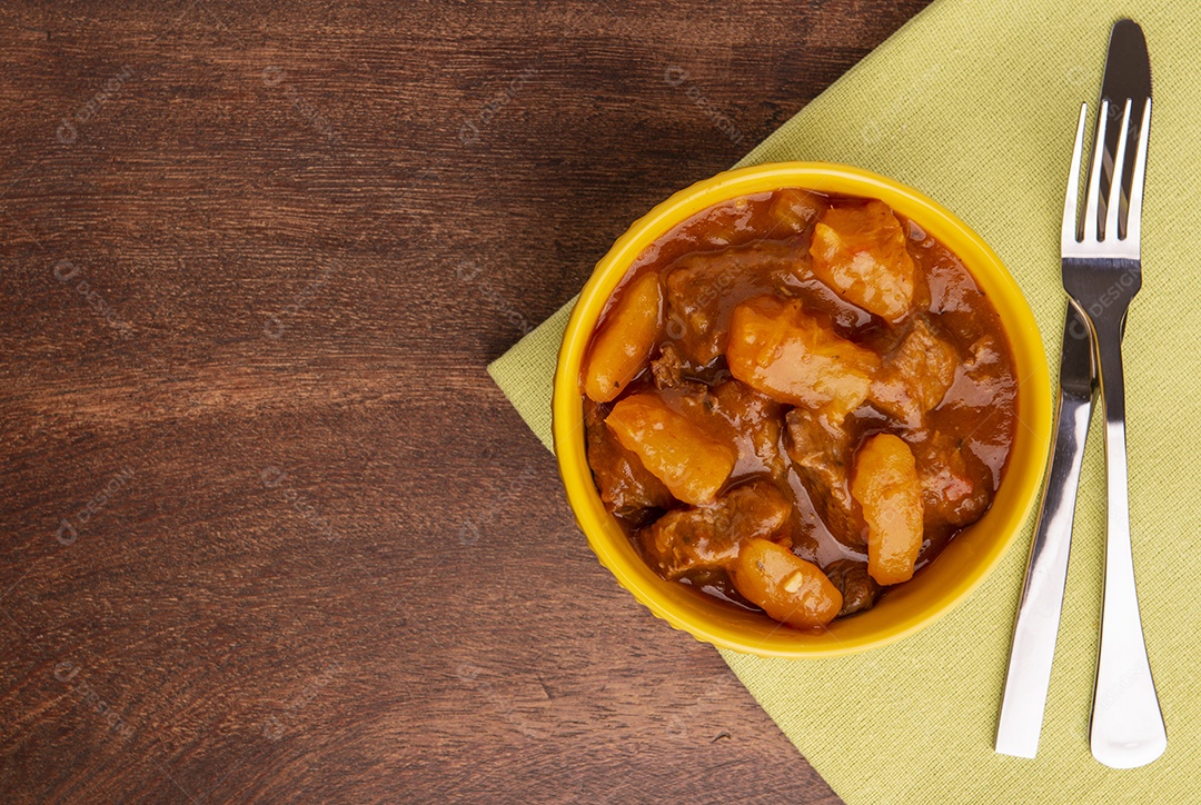 Prato com mandioca cozida e carne na mesa de madeira