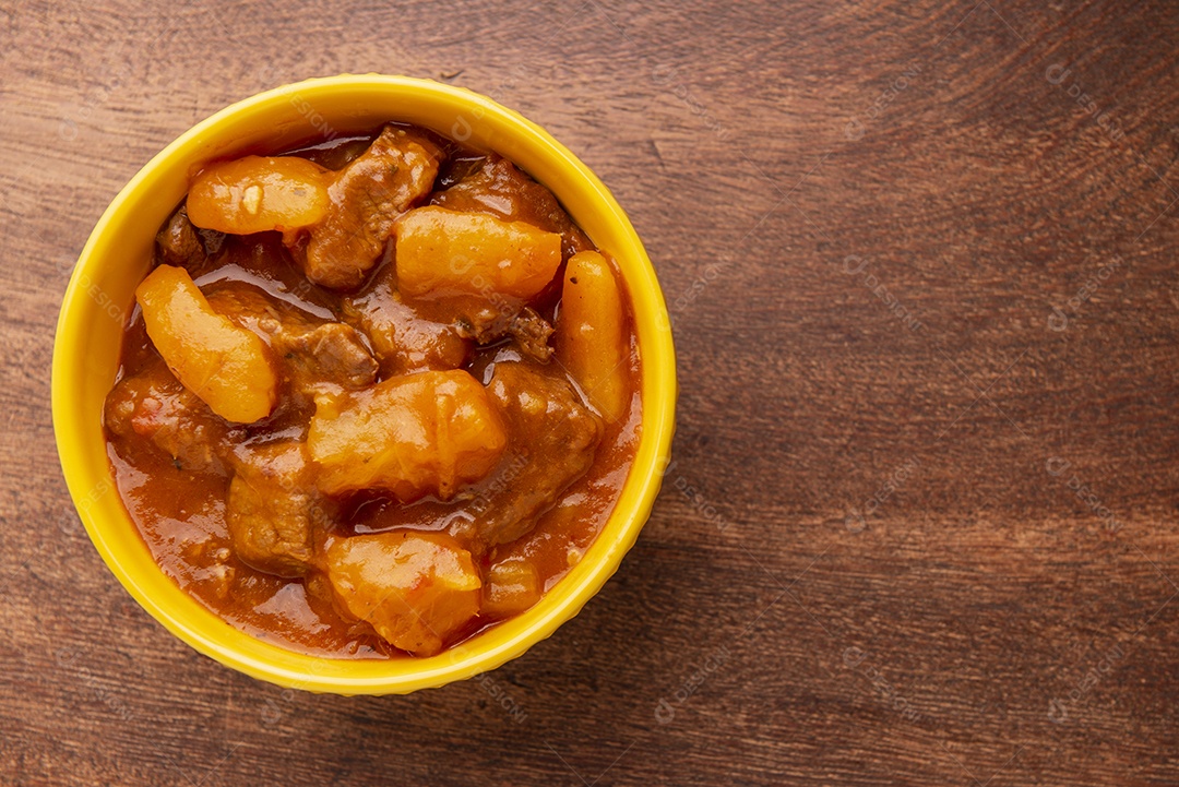 Prato com mandioca cozida e carne na mesa de madeira