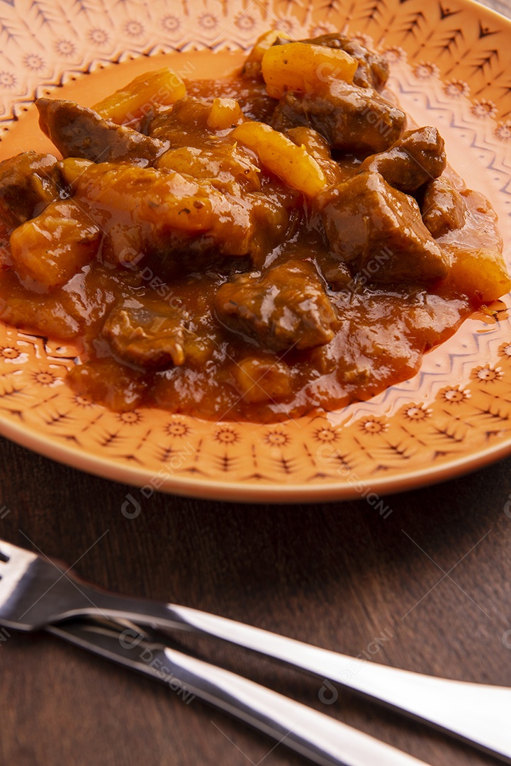 Prato com mandioca cozida e carne na mesa de madeira
