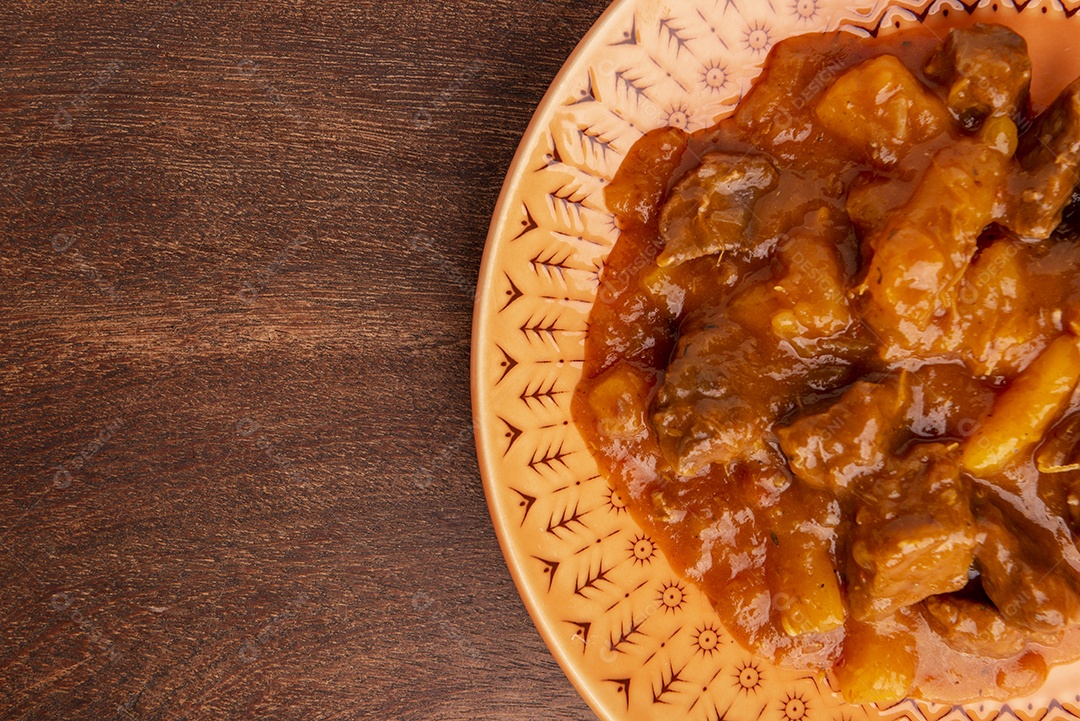Prato com mandioca cozida e carne na mesa de madeira