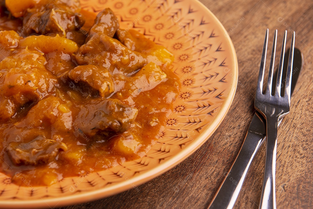 Prato com mandioca cozida e carne na mesa de madeira
