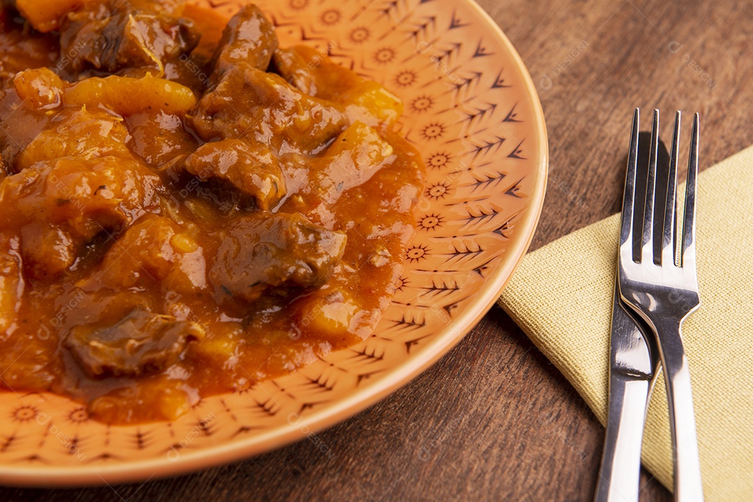 Prato com mandioca cozida e carne na mesa de madeira