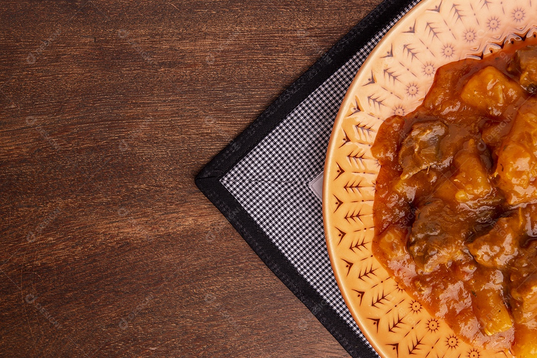 Prato com mandioca cozida e carne na mesa de madeira