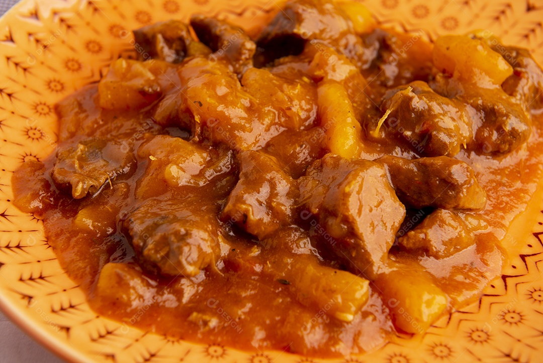Prato com mandioca cozida e carne na mesa de madeira