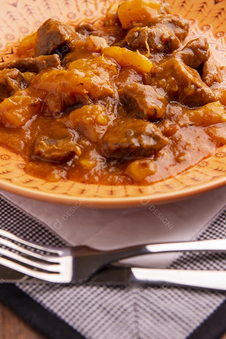 Prato com mandioca cozida e carne na mesa de madeira