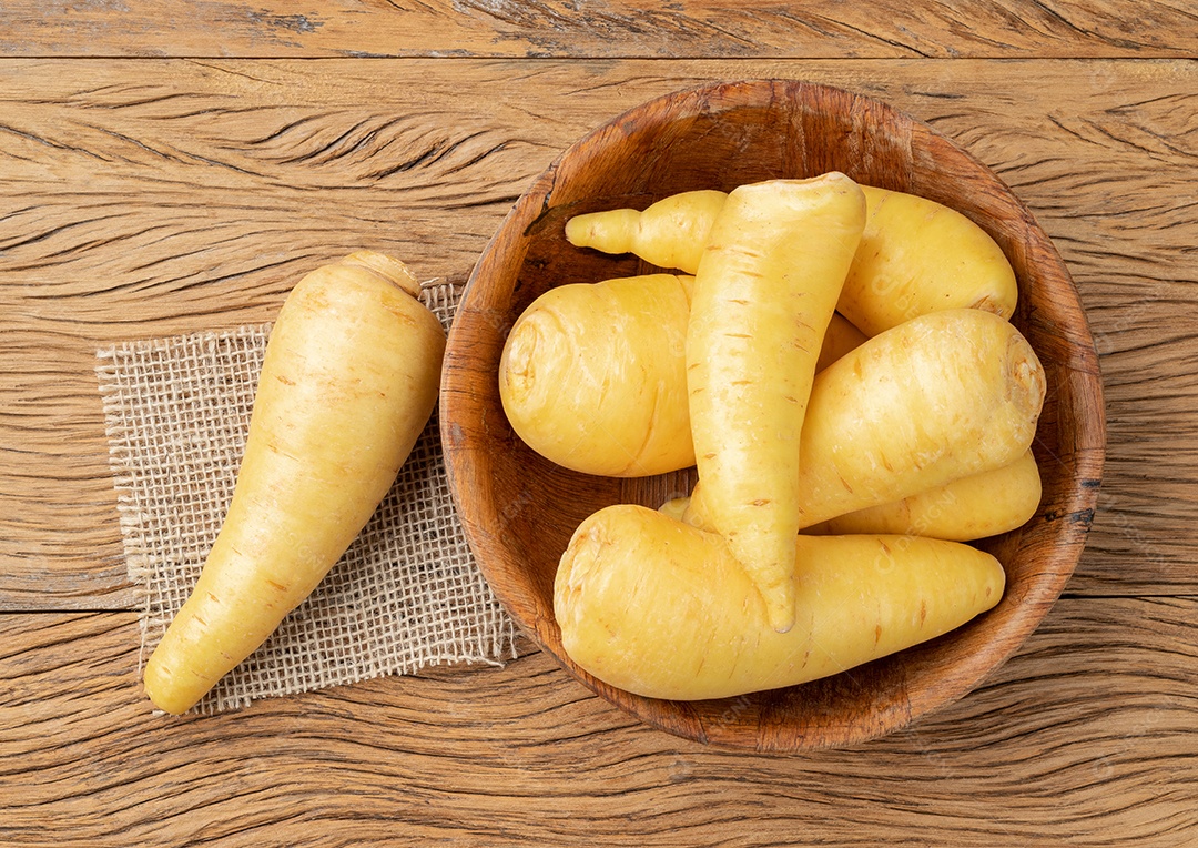 Mandioquinha crua ou arracacha em uma tigela sobre mesa de madeira