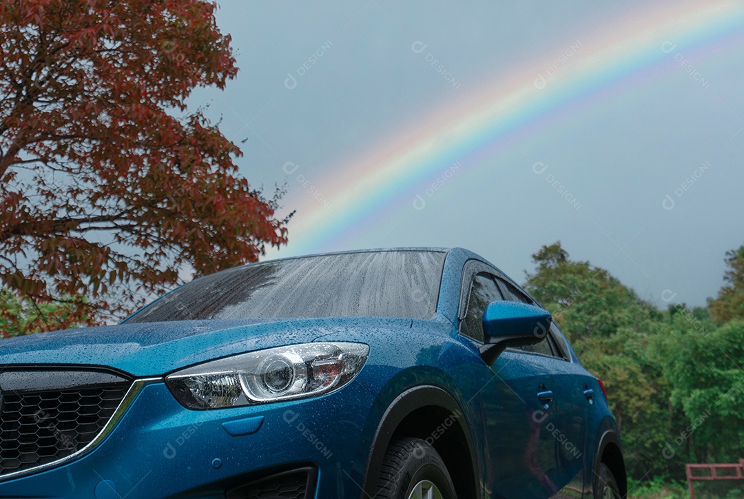 Carro SUV azul coberto com pingos de chuva contra floresta verde