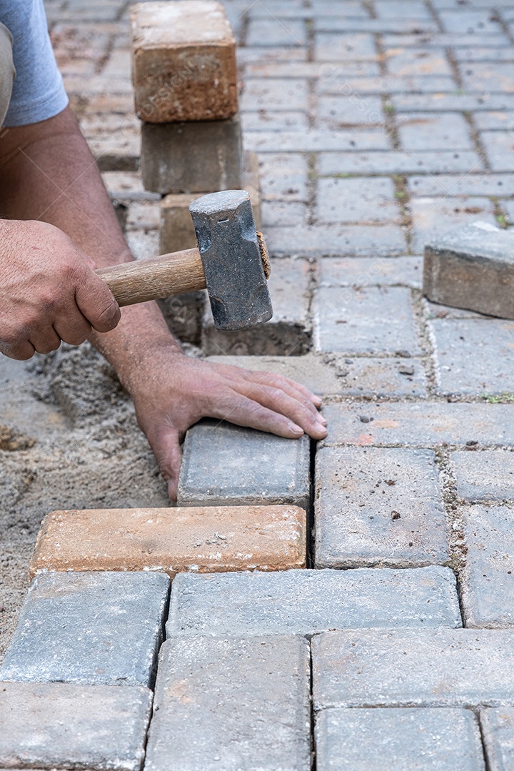 Brasileiro e trabalhador da construção civil batendo um pequeno martelo