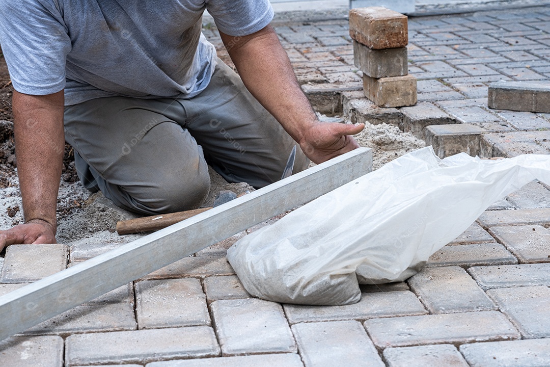 Brasileiro e pedreiro usando régua para verificar o nível de blocos de concreto.
