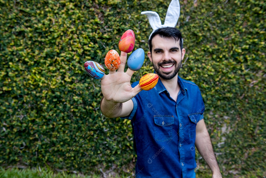 Homem com orelhas de coelho da páscoa segurando ovos de páscoa