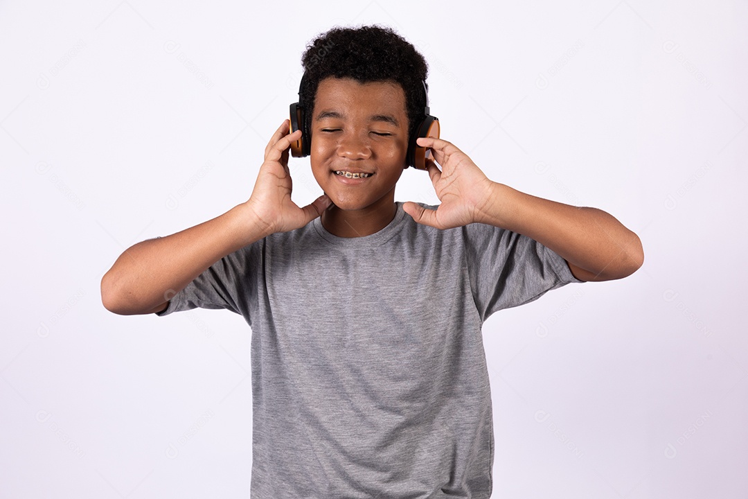 Menino jovem usando fones de ouvido ouvindo música sobre fundo isolado