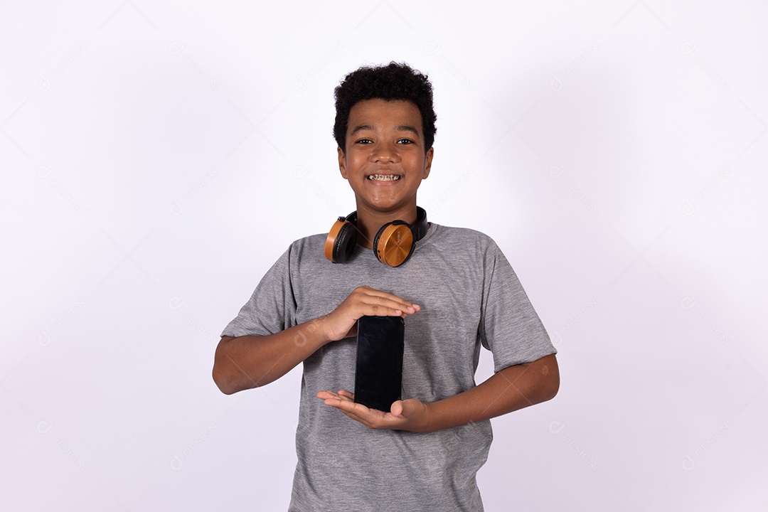 Menino jovem usando fones de ouvido segurando celular smartphone sobre fundo isolado