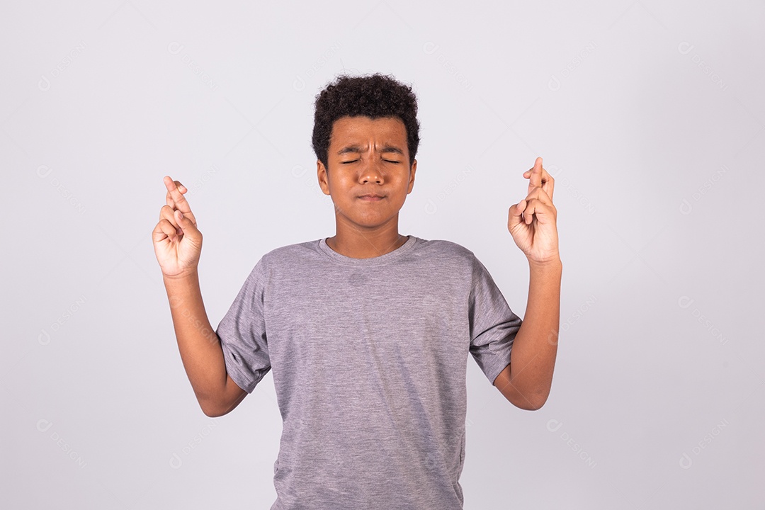 Menino jovem com dedos cruzados sobre fundo isolado