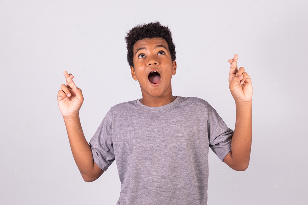 Menino jovem com dedos cruzados sobre fundo isolado