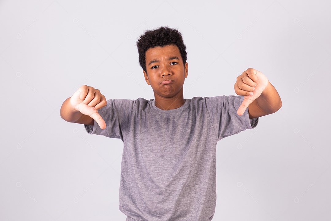 Menino jovem fazendo gestos polegares para baixo sobre fundo isolado