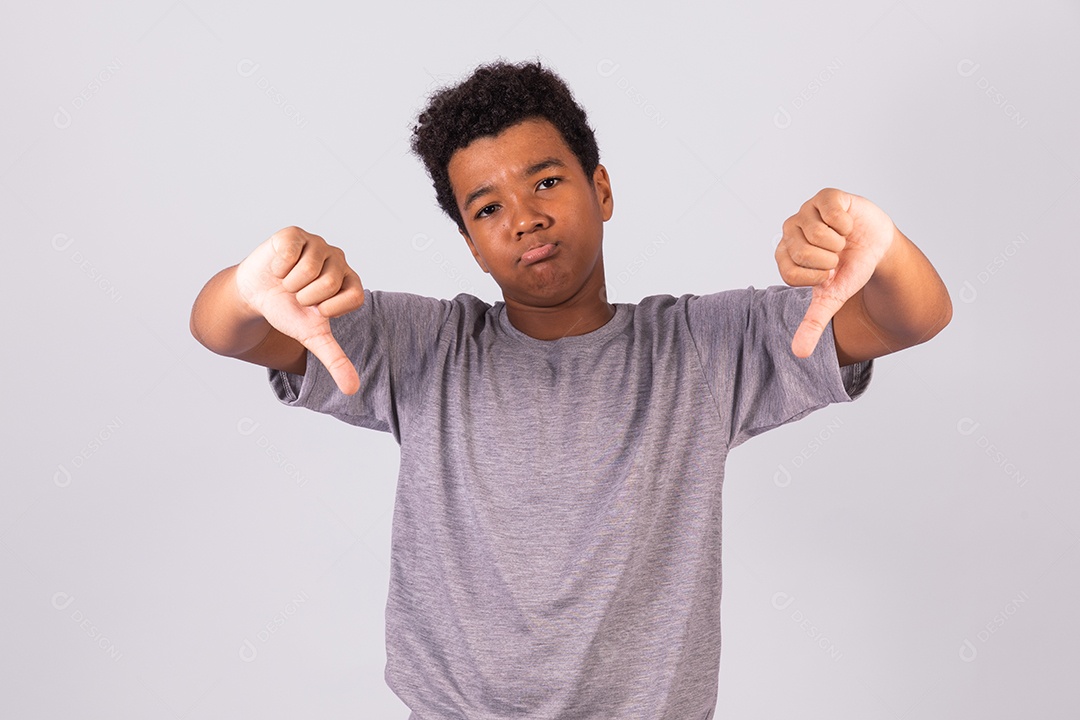 Menino jovem fazendo gestos polegares para baixo sobre fundo isolado