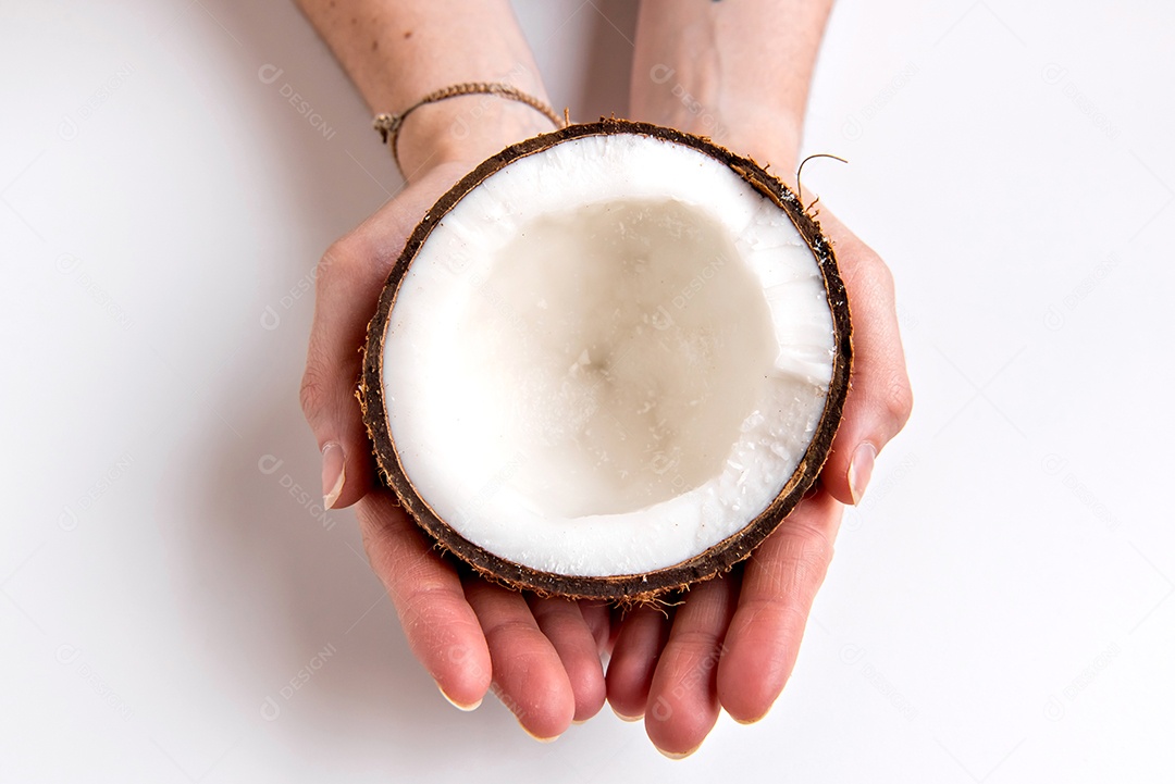 Mãos segurando coco meio cortado em fundo isolado