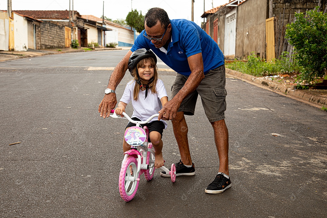 Pai ensinado sua filha a anda de bicicleta