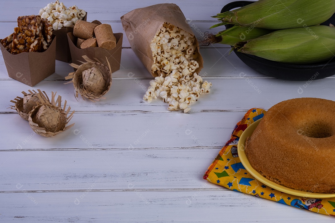 Milho verde e doces da festa junina na mesa de madeira branca
