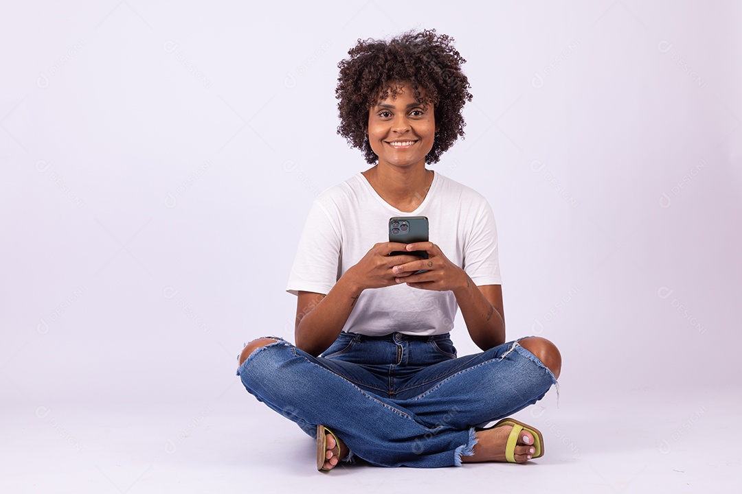 Linda mulher jovem garota com lindo cabelo afro mexendo em seu smartphone
