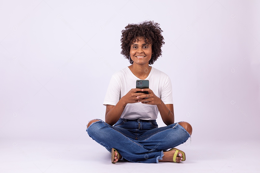 Linda mulher jovem garota com lindo cabelo afro mexendo em seu smartphone