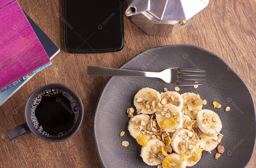 Prato com banana fatiada, granola, frutas cristalizadas e mel