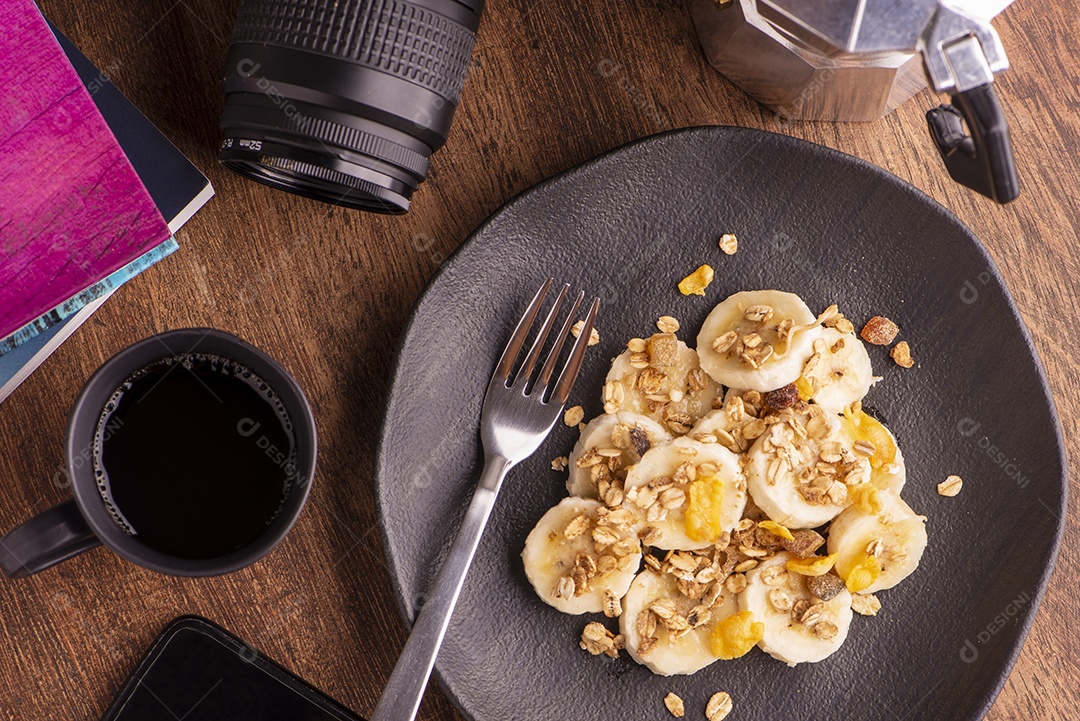 Prato com banana fatiada, granola, frutas cristalizadas e mel