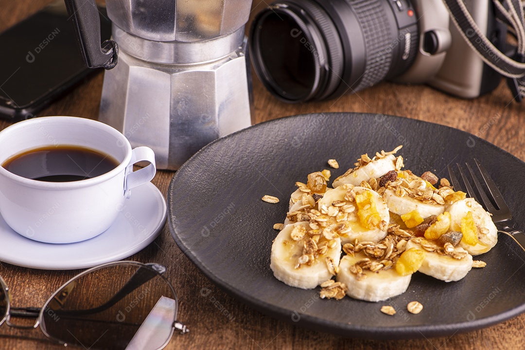 Prato com banana fatiada, granola, frutas cristalizadas e mel