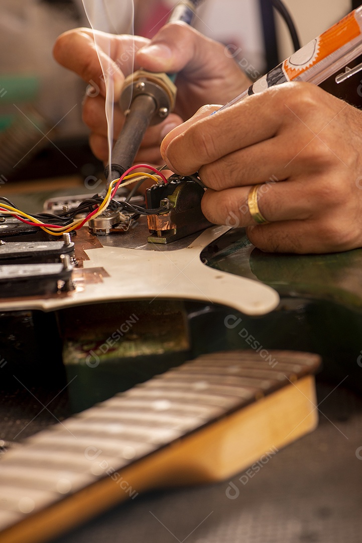 Luthier soldando um fio de guitarra em sua oficina