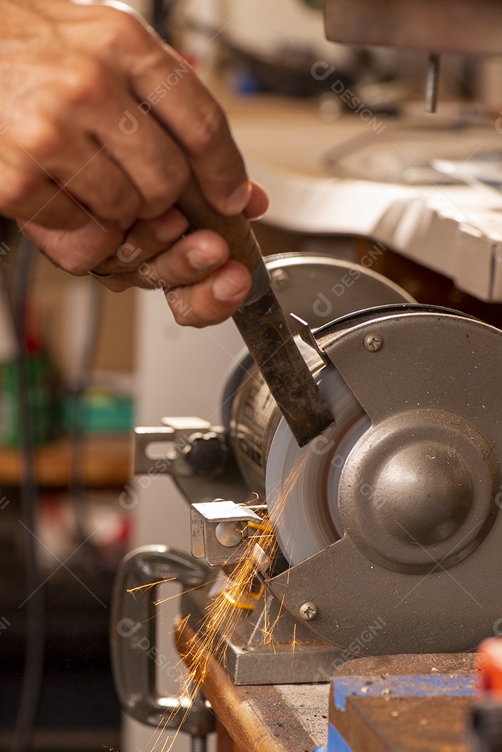 Luthier usando moedor para preparar peça de metal