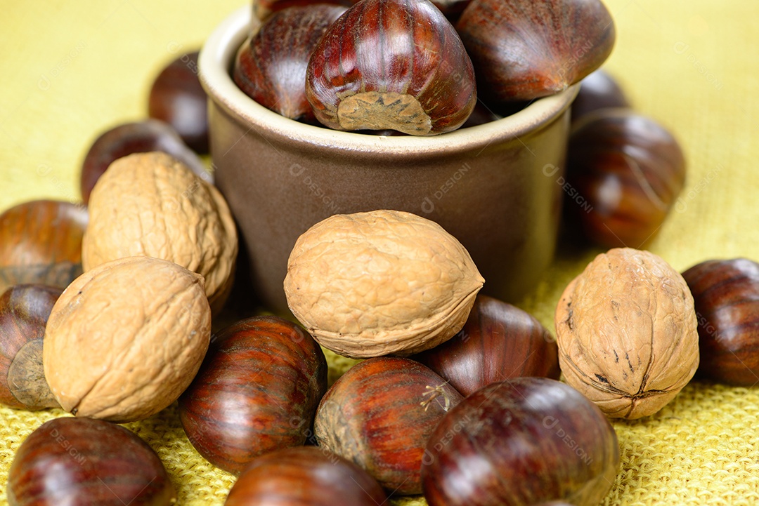 Castanhas portuguesas e nozes em pote de cerâmica sobre juta amarela
