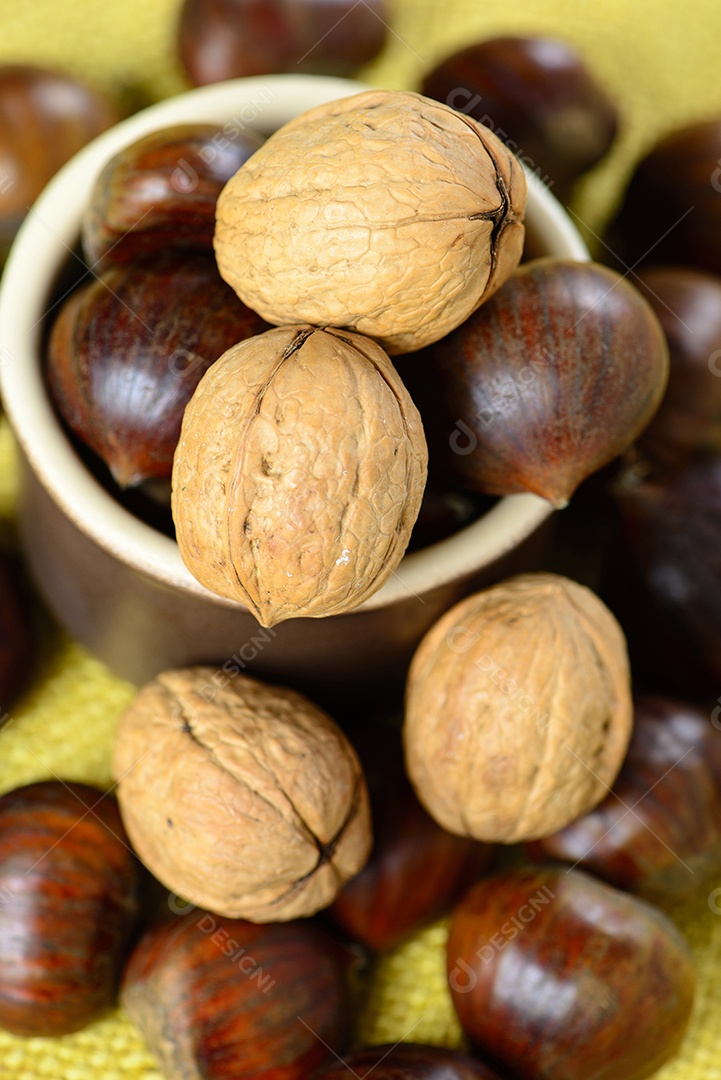 Castanhas portuguesas e nozes em pote de cerâmica sobre juta amarela